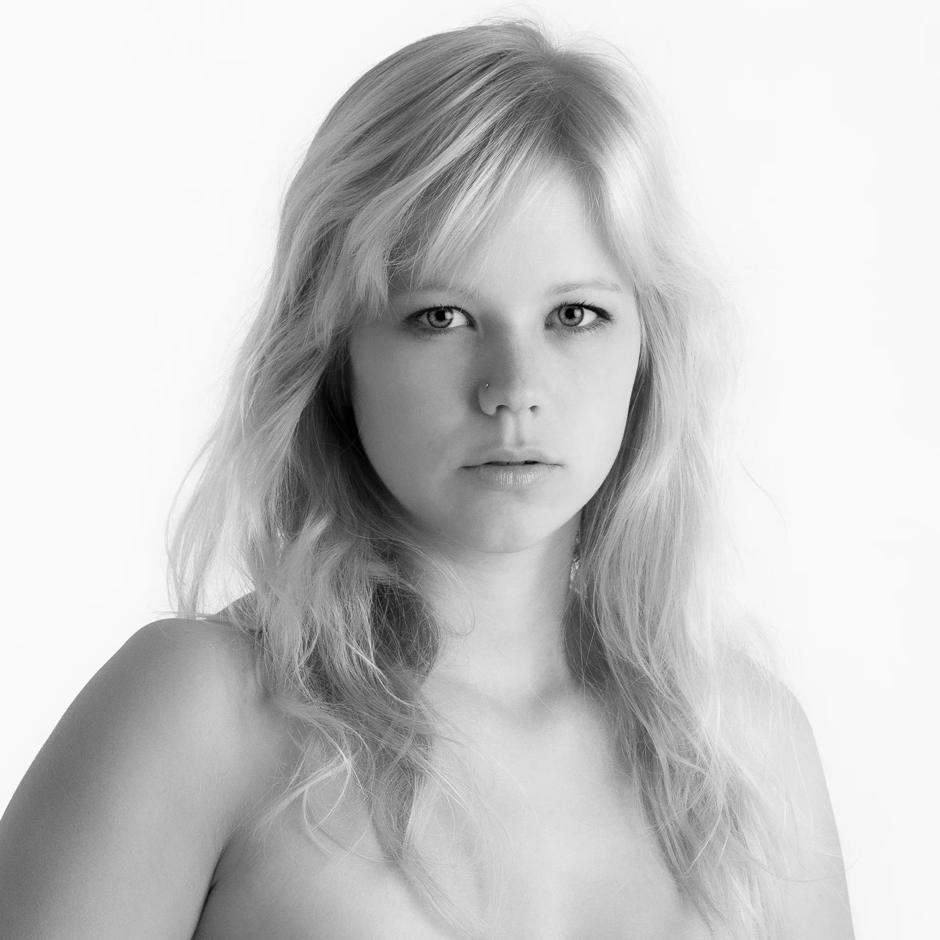 Schwarz-Weiß-Portrait: Gesicht und Schulter einer jungen Frau mit blonden, bis zum Brustansatz reichenden langen Haaren; klarer Blick direkt in die Camera